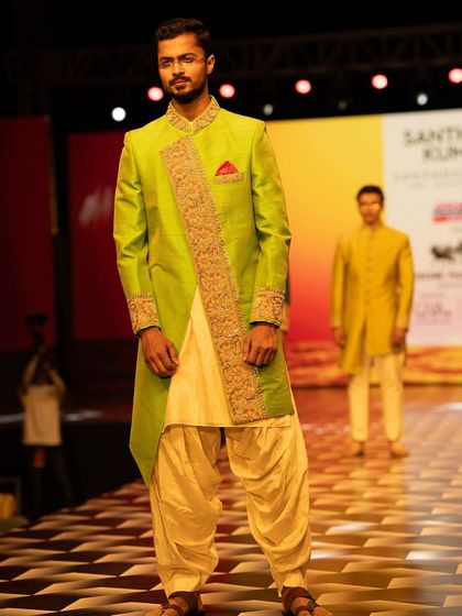 Posing on the runway in a bright, festive sherwani, perfect for wedding and celebration wear collections.