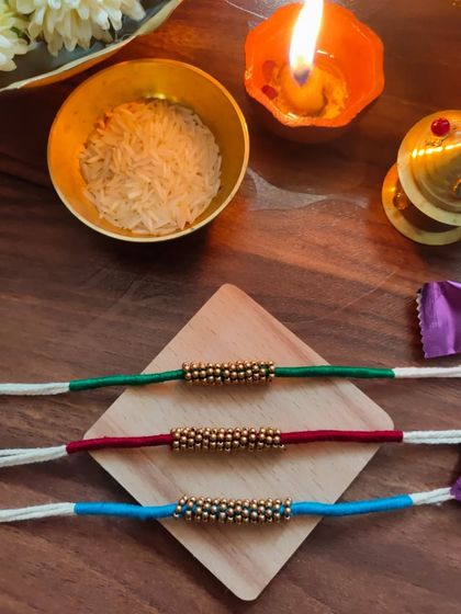 A set of simple and elegant rakhis made with thread and golden beads. These are available in green, red, and blue.
