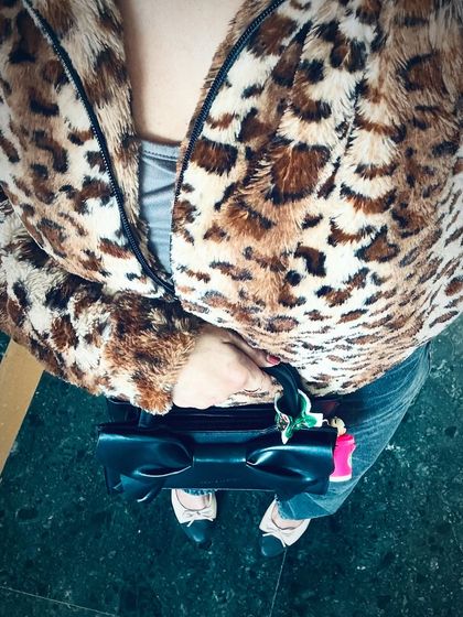 A top-down view of a bold winter outfit. A faux fur leopard print jacket adds a touch of glamour and personality to a simple base of jeans and a top.