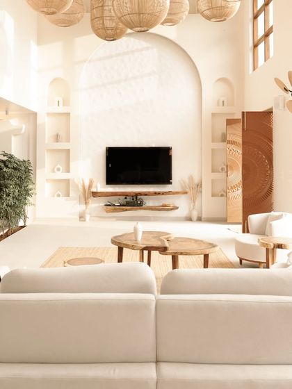 The main living area is defined by its soaring ceilings and an arched feature wall with built-in niches for curated decor. The design emphasizes natural light and an uncluttered aesthetic, making the large space feel serene and grounded.