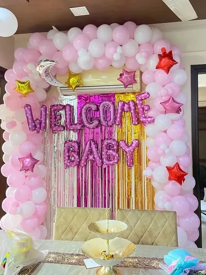 A classic "Welcome Baby" setup perfect for celebrating at home. We framed the main wall with a full balloon arch in pink and white, adding a shiny foil curtain and "Welcome Baby" letter balloons to create a festive and joyful photo corner.