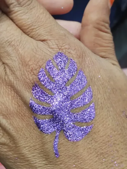A purple monstera leaf glitter tattoo. This trendy and stylish design is a great choice for both kids and adults.