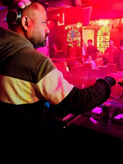 A focused moment during a Saturday night gig. The red lighting sets an intense mood as I line up the next big Bollywood track for the dance floor.