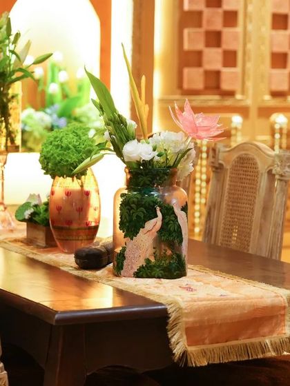 A dining setup from the puja, with elegant wooden furniture and custom floral centerpieces, continuing the theme of refined tradition.