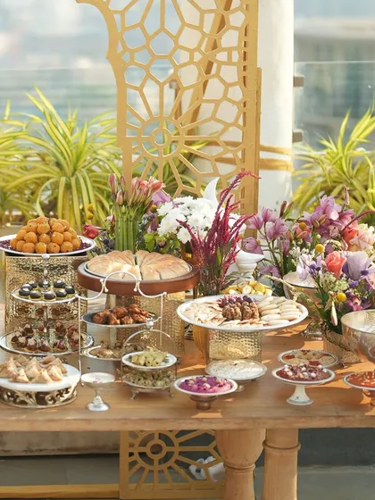 The full Iftaar grazing table, a stunning landscape of food, flowers, and elegant decor against a city skyline.