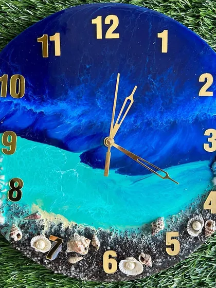 A deep blue ocean clock with a sandy shore and a variety of shells, perfect for any beach lover.