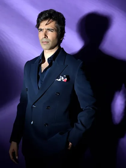 A portrait of Varun Mitra using dramatic, shaped lighting against a purple background. This technique creates a moody and sophisticated atmosphere.