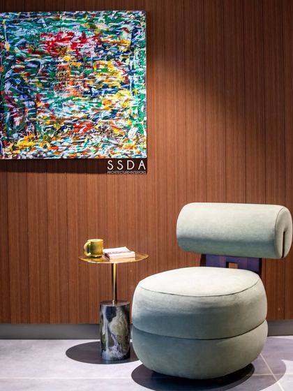 A quiet corner in our studio, perfect for a moment of thought. A comfortable chair is paired with a small side table and a vibrant piece of abstract art.
