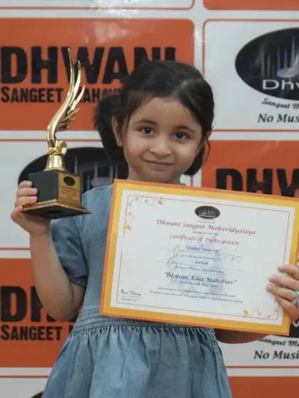 A little artist proudly holds her certificate and trophy.
