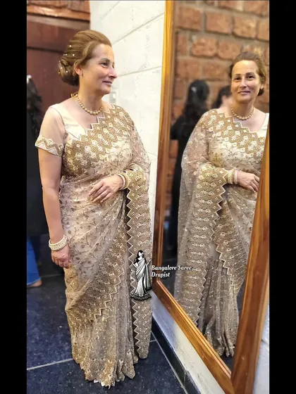 A partywear saree draping for a German client. She looks absolutely stunning in this embellished gold saree, ready for a wedding reception.