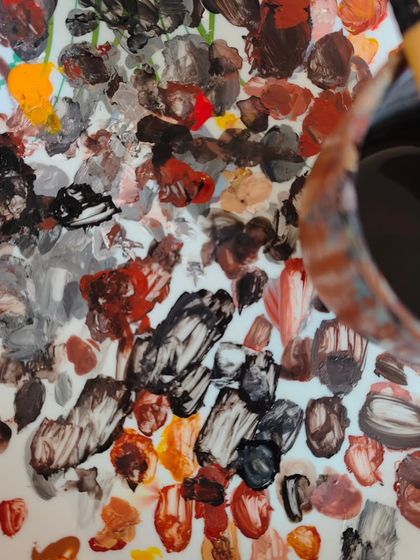 A close-up of a palette filled with a beautiful mess of earthy, mixed paints. This is where colors are born and stories begin.