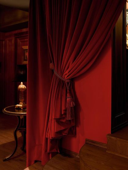 Heavy, tasseled velvet drapery conceals the entrance to the main bar, adding to the mystery. This detail is reminiscent of the 1920s flapper era, enhancing the narrative of a hidden, prohibition-style bar.