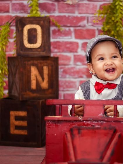 Pure happiness in our rustic brick wall setup. The combination of the red toy truck and the "ONE" blocks makes this a popular choice for energetic first birthday boys.