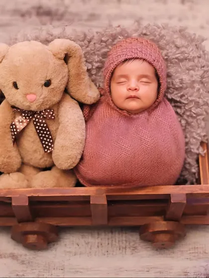 A sweet and simple composition featuring a swaddled newborn and a plush bunny friend. The potato sack pose is a classic way to keep the baby snug and secure, creating an adorable, compact portrait.