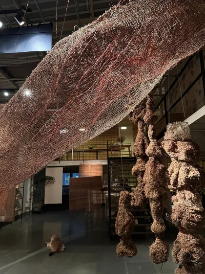 A view of our studio showing the scale of the 'Cu+Fibers' sculptures. A large, suspended woven piece made of copper and natural fibers interacts with smaller, denser forms below.