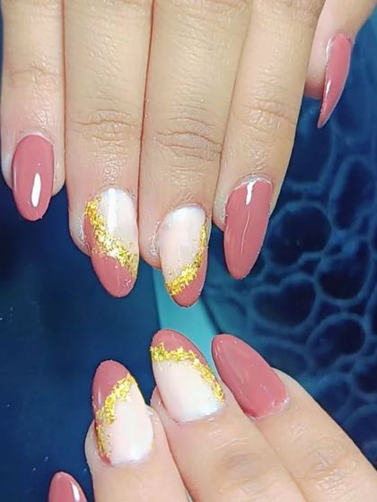 This elegant design features a dusty rose base on almond-shaped nails. The accent nails have a marbled look with a touch of gold foil for a sophisticated finish.