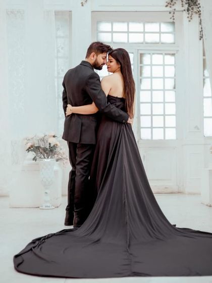 A dramatic shot of the couple, with the black gown's long trail spread out behind them.