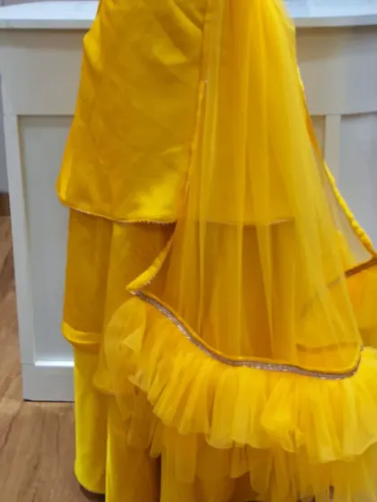 The back view of the custom yellow tiered skirt for a Haldi ceremony outfit. The layers of fabric create beautiful movement, and the net dupatta adds a touch of grace to the ensemble.