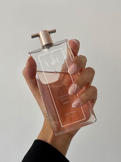 A simple, elegant shot of a hand holding a bottle of Yot perfume. This focuses on the bottle's clean design and the user's interaction with it, perfect for a minimalist brand aesthetic.