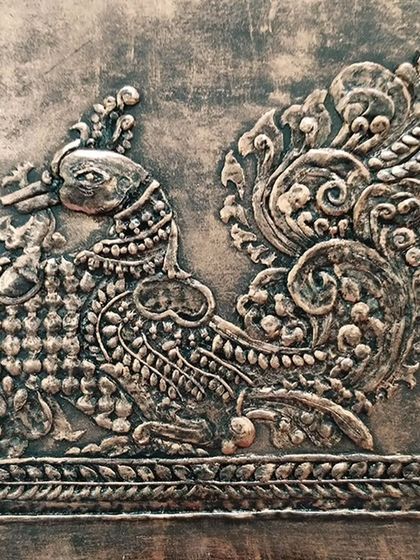 The finished relief artwork of a traditional Indian peacock, showcasing intricate details and a beautiful metallic finish.