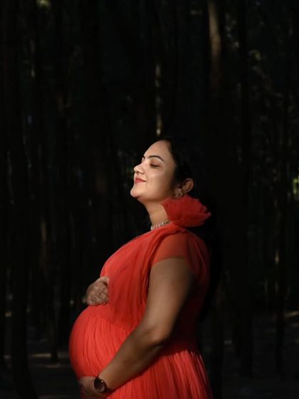 The contrast of this bright coral net gown against the dark woods creates a striking, fairytale-like image. The long trail adds to the enchanting effect.