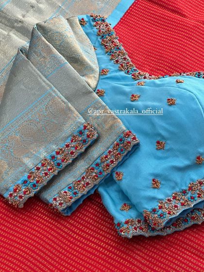 A light blue blouse with a contrasting red and gold embroidered border.