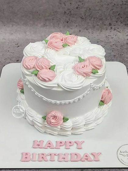 A simple yet beautiful birthday cake with vintage-style piping. The white swirls and pink roses create a delicate and timeless design.