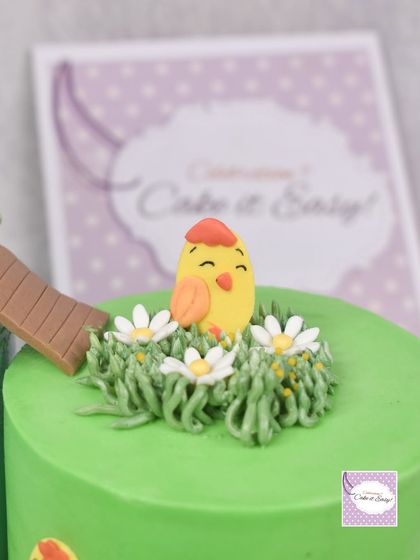 A close-up of a cute chick sitting in piped buttercream grass.