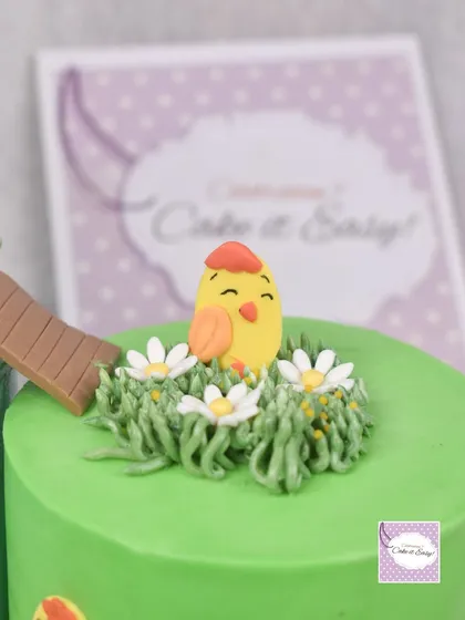 A close-up of a cute chick sitting in piped buttercream grass.