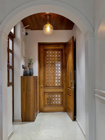 The beauty is in the details. This entryway features an intricately carved wooden door and a simple console table, demonstrating how pulling hues and materials from your home's existing scheme creates a cohesive first impression.