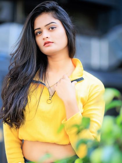 A confident and modern outdoor portrait. The bright yellow top and her direct gaze create a bold and eye-catching image.