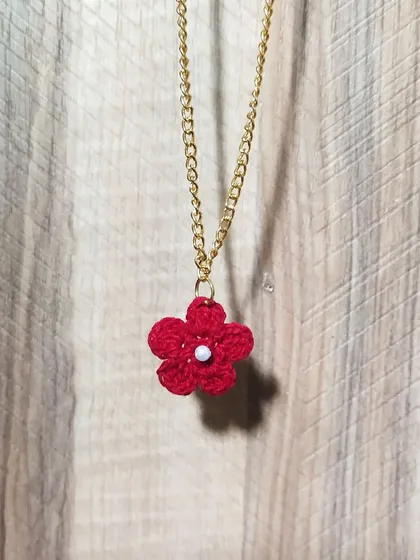 This simple red flower pendant is a basic yet beautiful accessory. It hangs from a gold-tone chain and adds a small, handmade pop of color to your neckline.