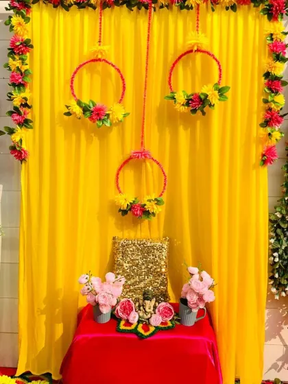 A bright and cheerful Ganpati corner featuring a vibrant yellow backdrop. I used hanging floral rings and lush green vines to add a fresh, natural element to the decoration, creating a simple yet beautiful space for the idol.