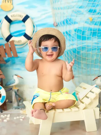 A cool and confident pose from the 'Beach Baby' shoot, with the little one leaning back on his chair with sunglasses.