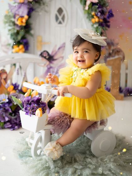 A big, happy smile from the birthday girl on her little white tricycle.