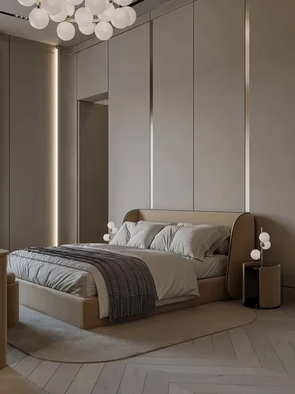 This view shows the herringbone-patterned wood floor and the soft, curved lines of the bed and side table, adding to the room's gentle and luxurious feel.
