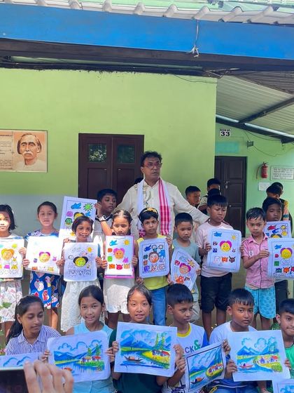 A group of proud young artists at the Doomdooma college workshop, holding up their paintings for a group photo. We explored both cartooning and landscape art.