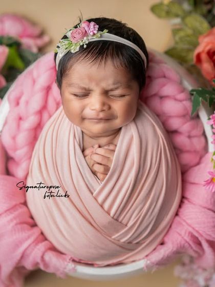 A precious newborn expression, captured while the baby is wrapped snugly in pink.