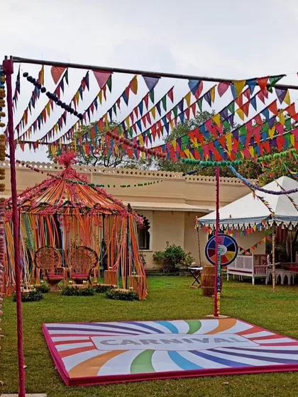 A full-blown carnival theme for a fun and colorful Mehendi party. This outdoor setup includes a decorated tent for the couple, a custom dance floor, and vibrant bunting flags.