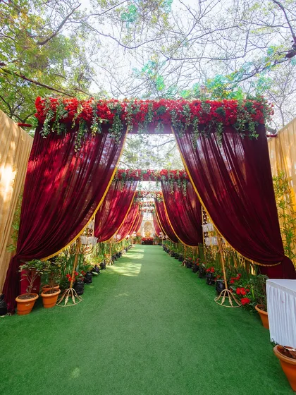 A grand and dramatic entrance for a wedding ceremony, draped in rich red velvet and topped with lush red roses. This creates a royal and inviting welcome for guests.
