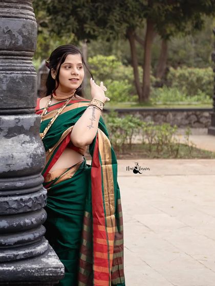 A graceful solo portrait of the mother to be in a stunning green and red saree. We wanted to capture her elegance and strength against the backdrop of the dark, traditional stone pillars.