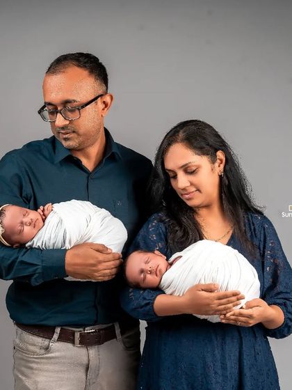 A tender moment as new parents each hold one of their newborn twins. This pose beautifully captures the beginning of their journey as a family of four, highlighting the individual bond with each baby.