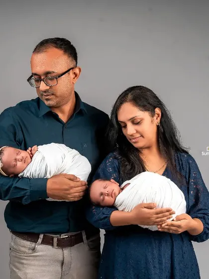 A tender moment as new parents each hold one of their newborn twins. This pose beautifully captures the beginning of their journey as a family of four, highlighting the individual bond with each baby.