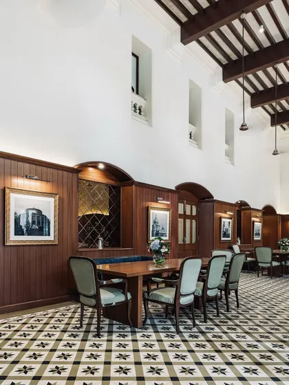 For the historic Bangalore Club, we focused on restoring its colonial grandeur while updating it for modern use. This dining area features high ceilings with exposed wooden beams, classic wood-paneled walls, and custom patterned floor tiles that honor the club's 150-year legacy.