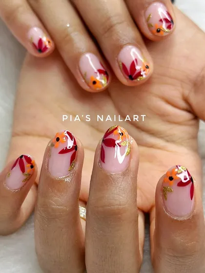 Beautiful hand-painted autumn flowers on natural nails. The warm tones and delicate gold foil flakes are perfect for the season.