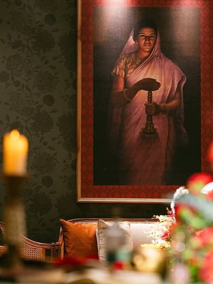 A close-up of a table setting, with a dramatic floral arrangement and a painting in the background. The focus is on creating a rich, sensory experience for guests.