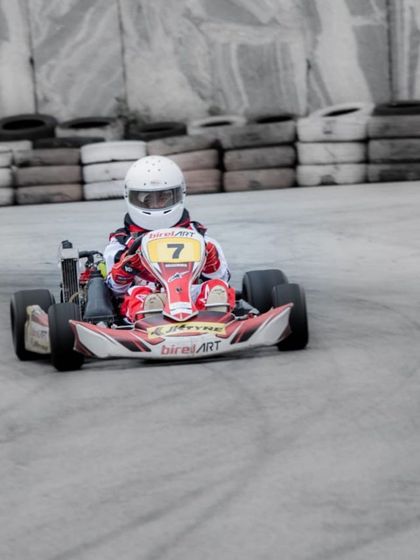 A Birel ART driver in kart number 7 navigates a concrete-lined section of the track during the Rotax Indian Championship.