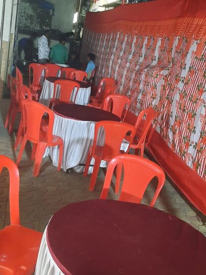 Round tables with covers set up for a birthday party inside a pandal.