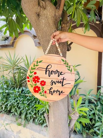 Another look at our 'Home Sweet Home' wooden sign, hanging on a tree. The rustic wood grain and hand-painted flowers make this a beautiful and welcoming piece for your entrance.