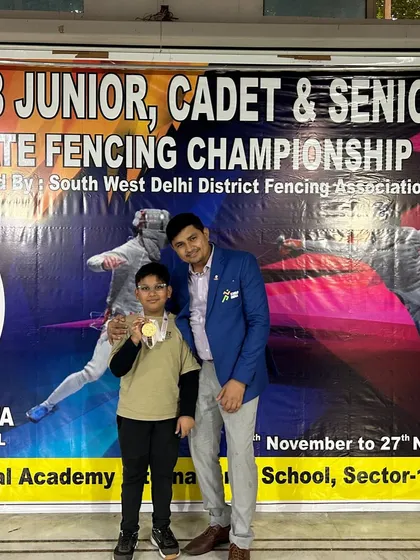 A proud coach with a gold medalist from the sub-junior boys' foil event at the Delhi State Championship. This one-on-one mentorship is key to our students' growth.